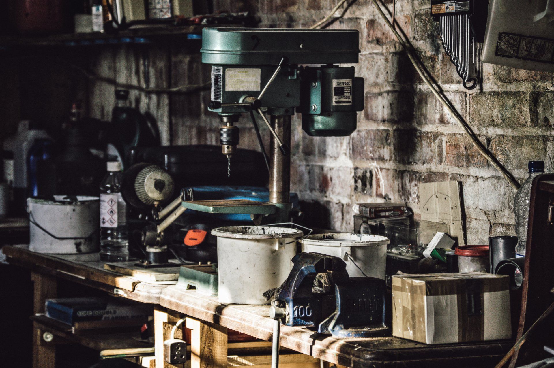 Une perceuse est posée sur une table en bois dans un garage.